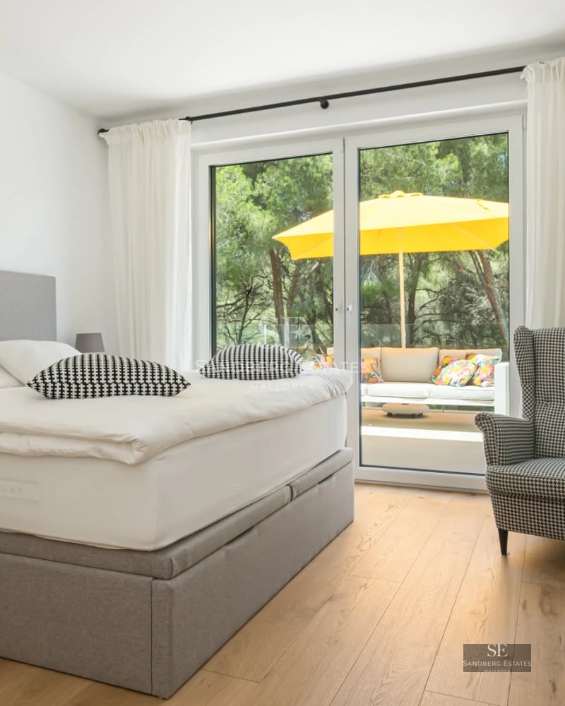 Spacious living room with balcony and sea view. Modern furniture, light wood floors, and abundant natural light.