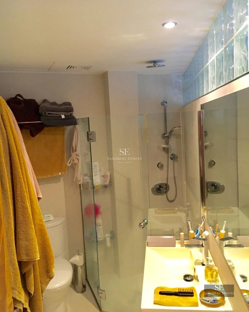 Large reflecting pool bordered by lawn and a modern villa with large windows reflecting sunlight.