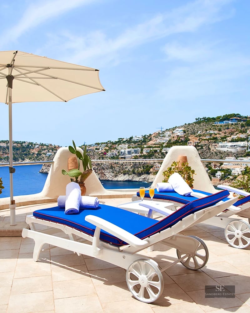 Spacious terrace with pool, sun loungers, and panoramic sea views. Modern design with glass railing and wooden flooring.