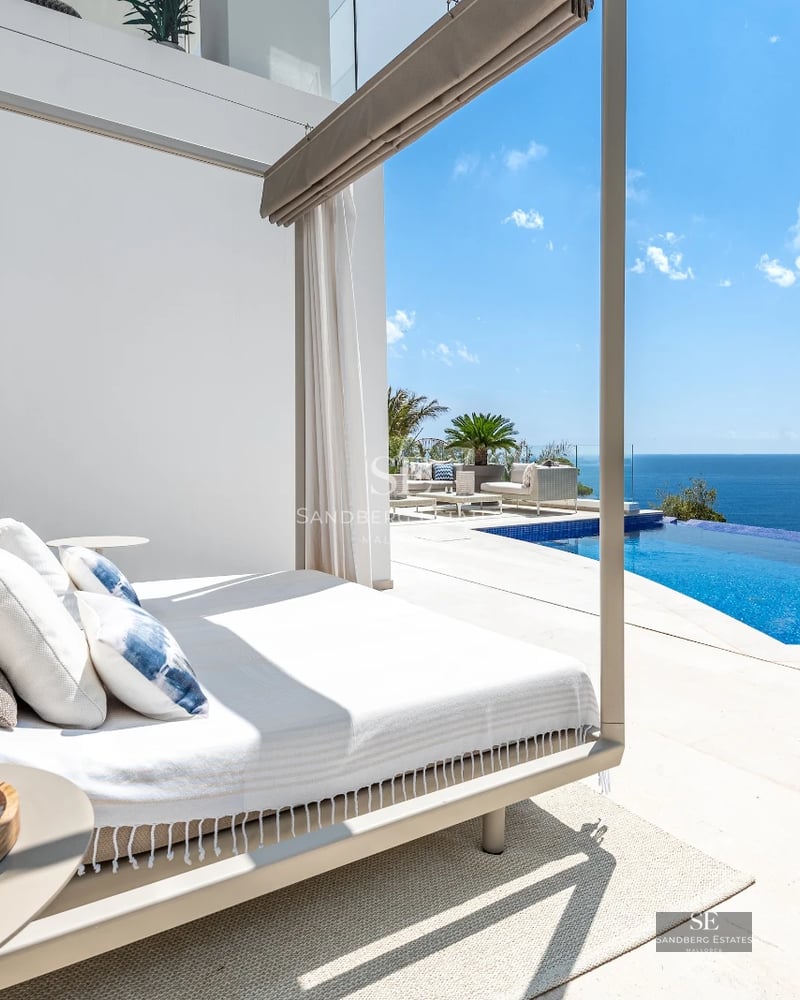 Balcony with panoramic sea views. Modern design, glass railing, wooden flooring, stylish outdoor furniture.