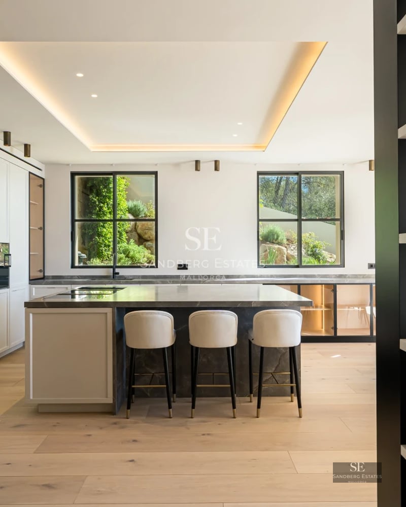 View of an infinity pool overlooking the sea from a modern villa. Loungers, umbrellas, and lush vegetation.