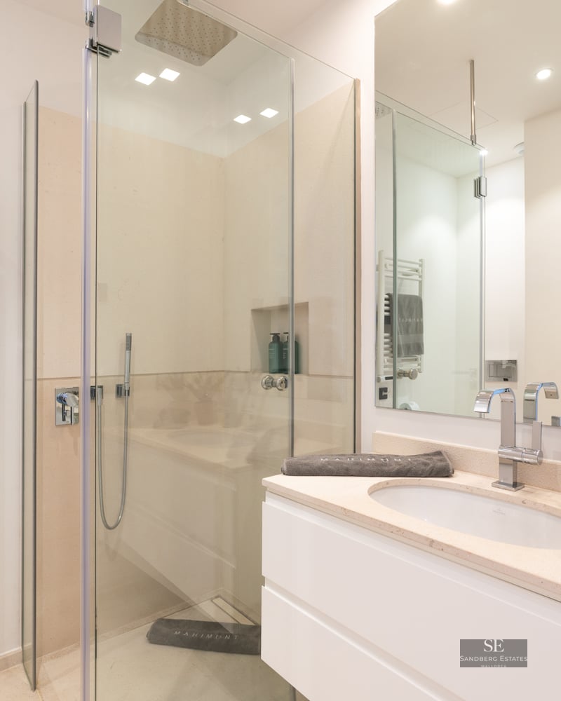 Modern bathroom featuring a glass walk-in shower, white vanity with chrome faucet, and a heated towel rack.