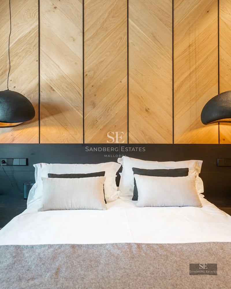 View of infinity pool with stone edge, sun loungers and lush vegetation. Modern and elegant design with clear blue sky.