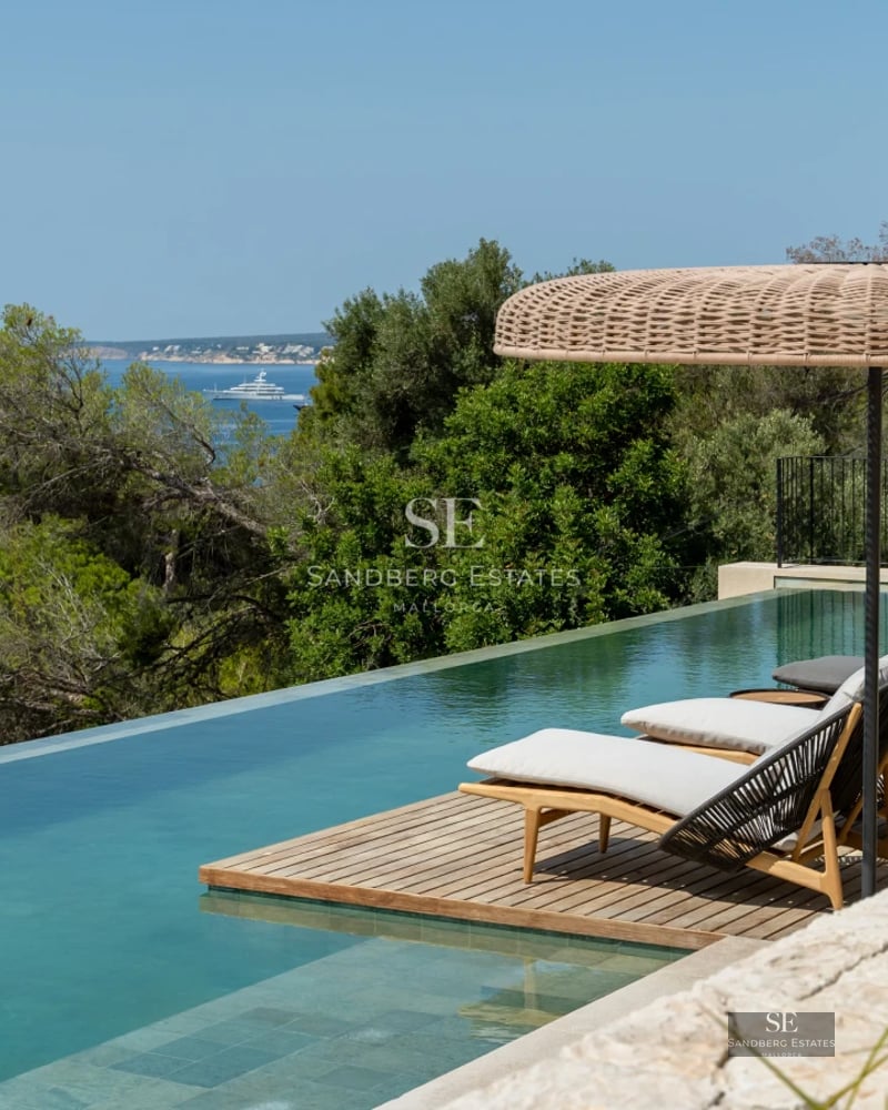 Exterior view of a modern villa featuring an infinity pool, expansive terraces, lush greenery, and minimalist architecture.