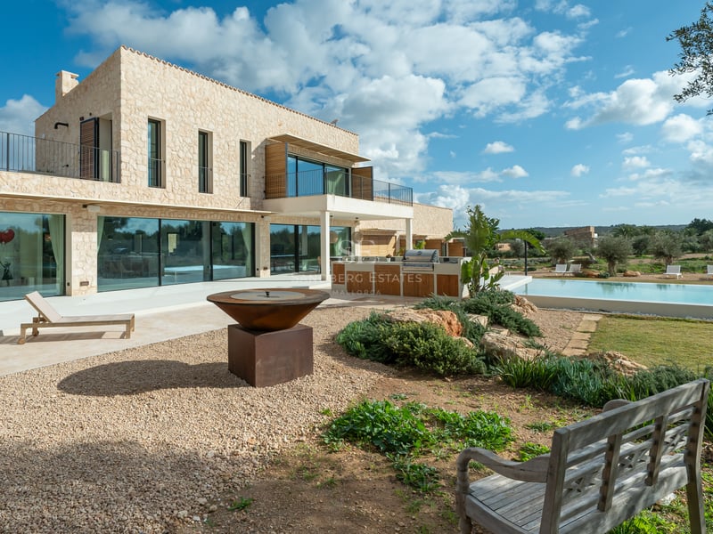 Modern tvåvåningsvilla med naturstensfasad, stora glaspartier, exklusivt utekök och designad eldstad.