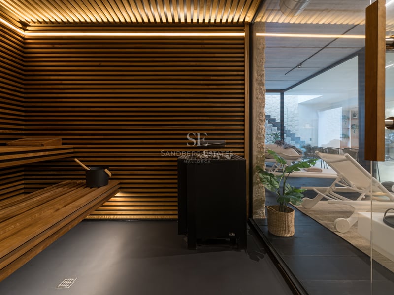 Interiör av en lyxig bastu med horisontella träribbor, integrerad LED-belysning och utsikt mot relaxavdelningen.