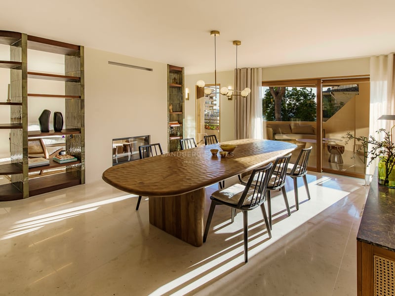 Sonniges Esszimmer mit strukturiertem Holztisch, schwarzen Stühlen, Marmorboden und Terrassenzugang.