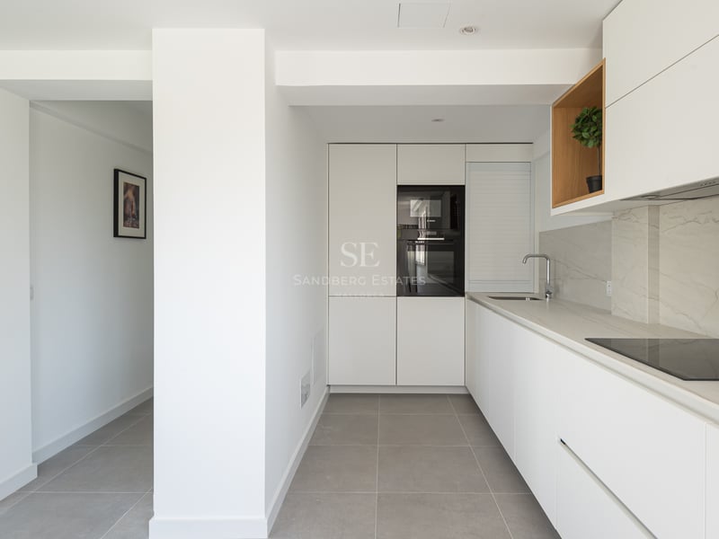 Cuisine blanche minimaliste, plans de travail effet marbre, carrelage gris et four Bosch encastré.