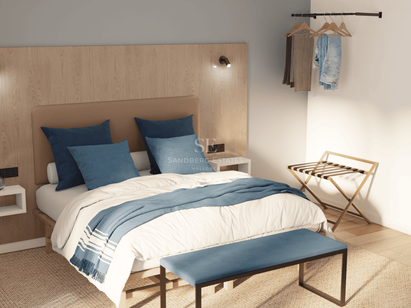 Chambre minimaliste avec tête de lit en bois clair, literie bleue, banc au pied du lit et miroir ovale.