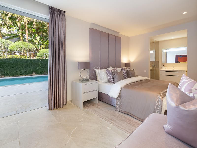 Modernes Schlafzimmer mit Doppelbett, gepolstertem Kopfteil, Marmorboden und direktem Zugang zum Außenpool.