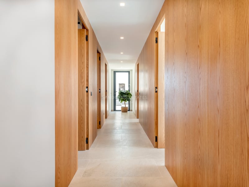 Couloir moderne lumineux avec des panneaux en bois de chêne du sol au plafond et des portes affleurantes.