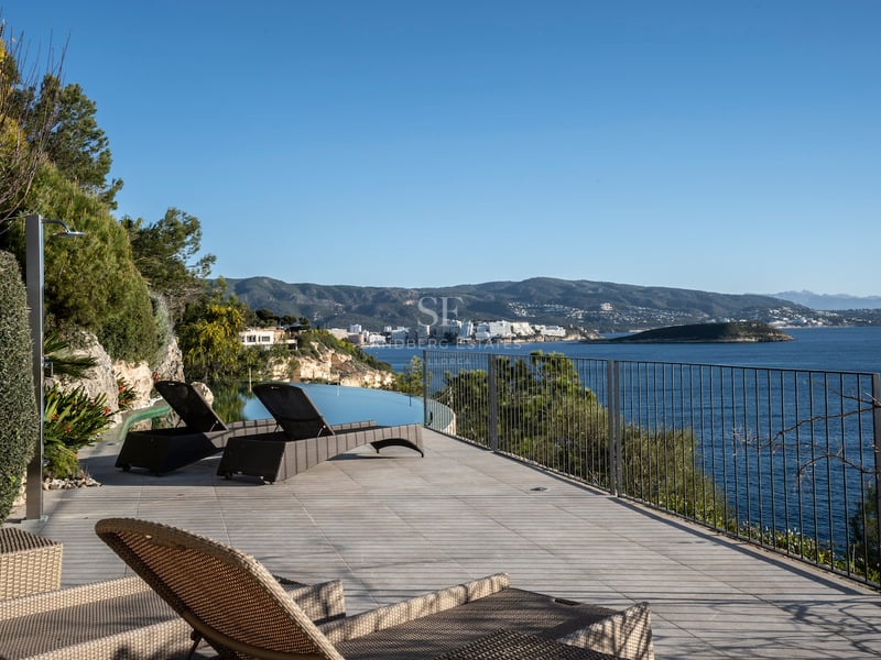 Luxuriöse Sonnenterrasse mit Liegen, Infinity-Pool und Panoramablick auf das Mittelmeer und die Berge.