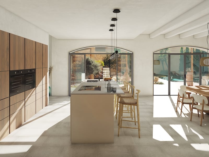 Cuisine moderne à aire ouverte avec îlot central, menuiserie en noyer et portes vitrées cintrées donnant sur un patio.