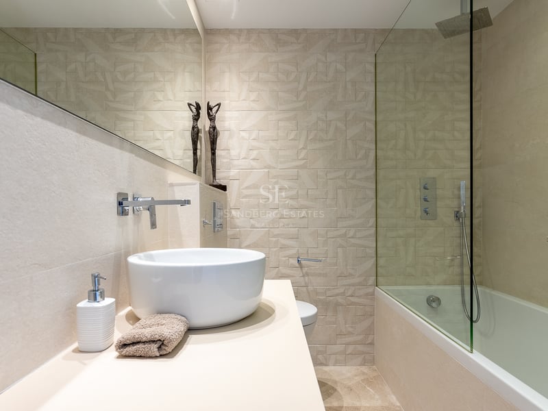 Modernes Badezimmer mit Aufsatzwaschbecken, großem Spiegel und geometrisch strukturierter Fliesenwand.