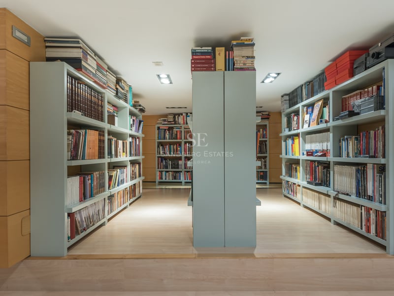 Bibliothèque moderne avec boiseries en chêne clair et étagères intégrées vert sauge.