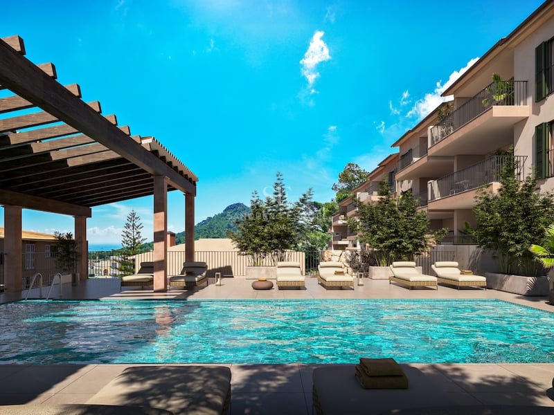 Outdoor swimming pool with sun loungers, a wooden pergola, and mountain views under a clear blue sky.