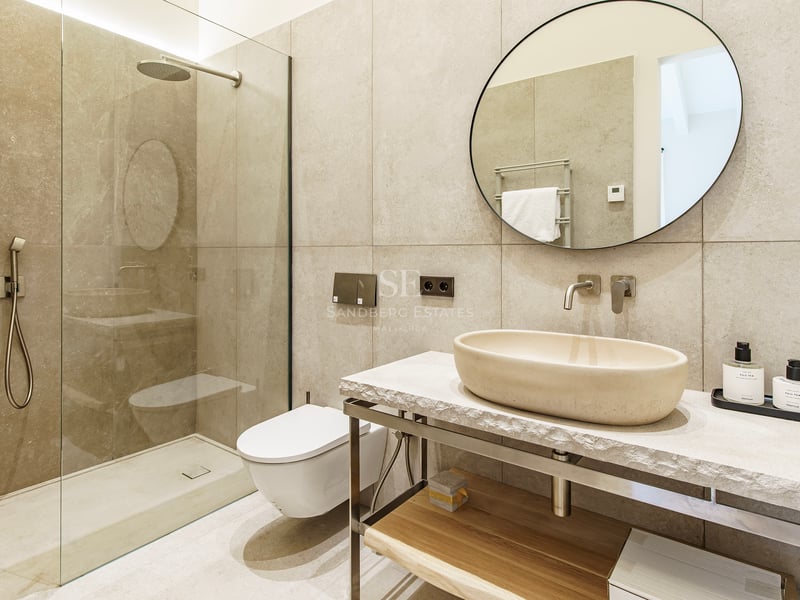 Zeitgenössisches Badezimmer mit Stein-Aufsatzwaschbecken, rundem Spiegel und begehbarer Glasdusche.