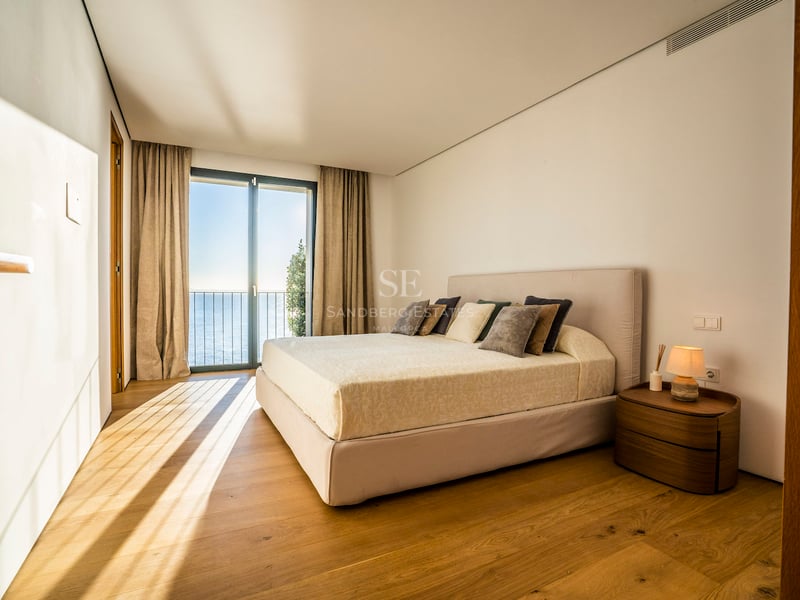 Modernes Schlafzimmer mit Eichenparkett und bodentiefen Glastüren, die den Blick auf das Mittelmeer freigeben.