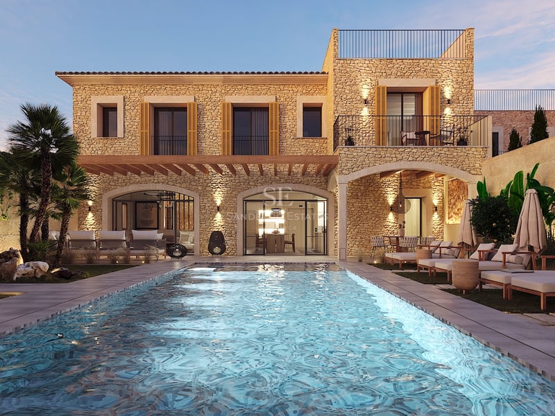 Vue nocturne d'une villa en pierre avec piscine éclairée, bains de soleil et palmiers sous un ciel de crépuscule.