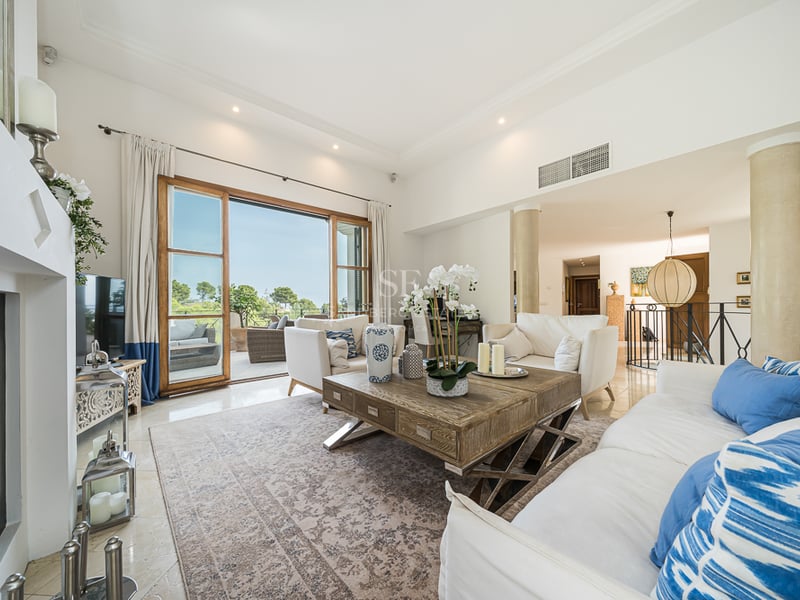 Ljust vardagsrum med vita soffor, ett rejält soffbord i trä och skjutdörrar i glas mot en terrass.