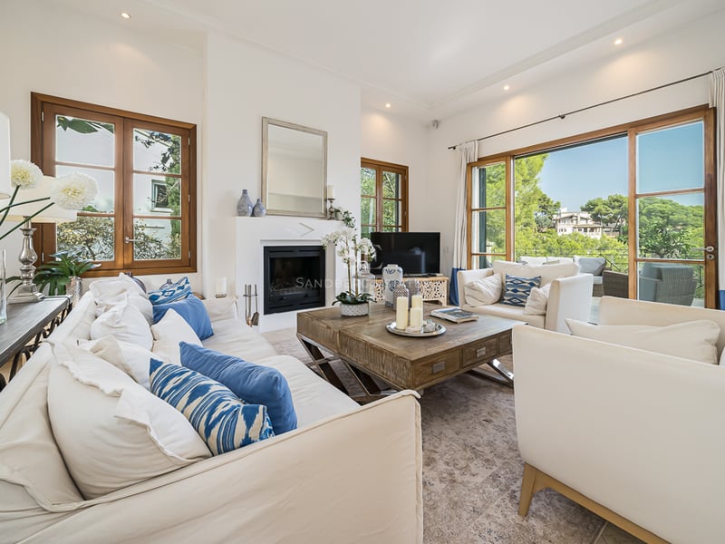 Ljust vardagsrum med vita soffor, blå detaljer, ett stort soffbord i trä och inbyggd öppen spis.