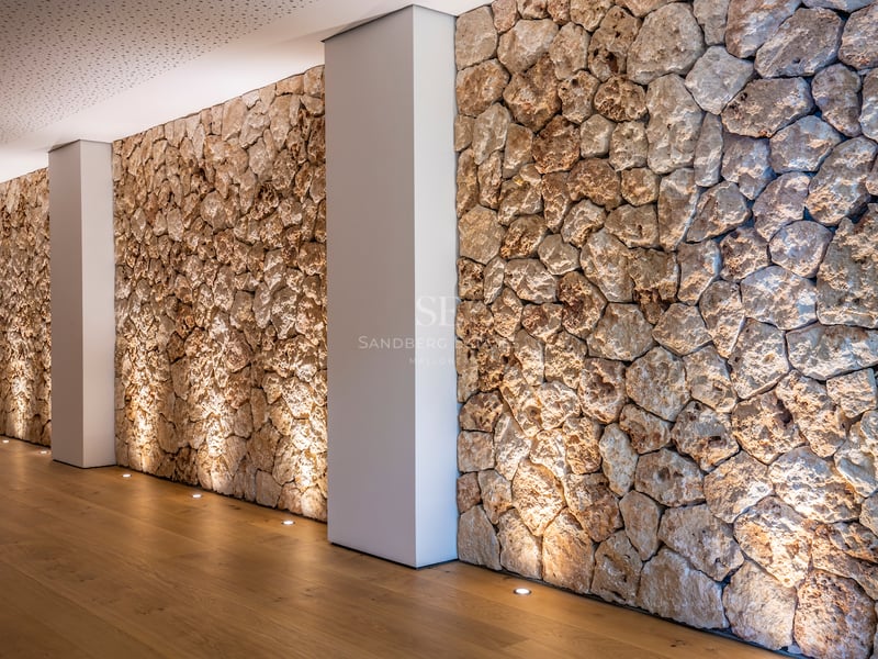 Innenflur mit rustikaler Natursteinwand, Bodenstrahlern und hellem Eichenparkett.