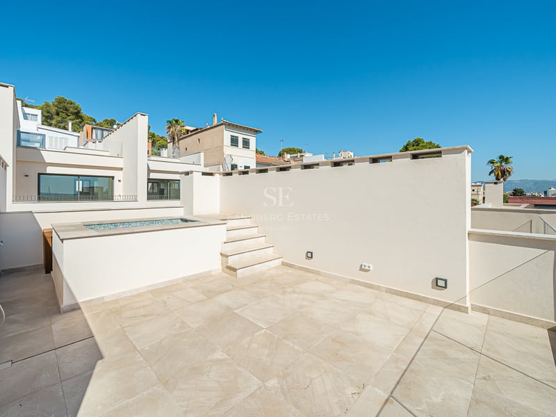 A sun-drenched rooftop terrace featuring a natural stone deck and a built-in plunge pool under a clear blue sky.