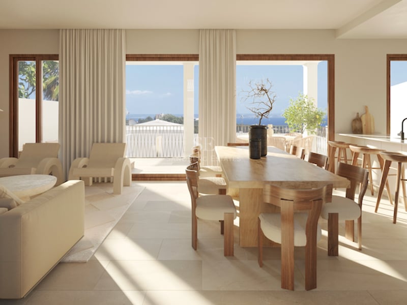 Moderner Essraum mit Holztisch und bodentiefen Fenstern, die auf eine Terrasse mit Blick auf das Meer führen.