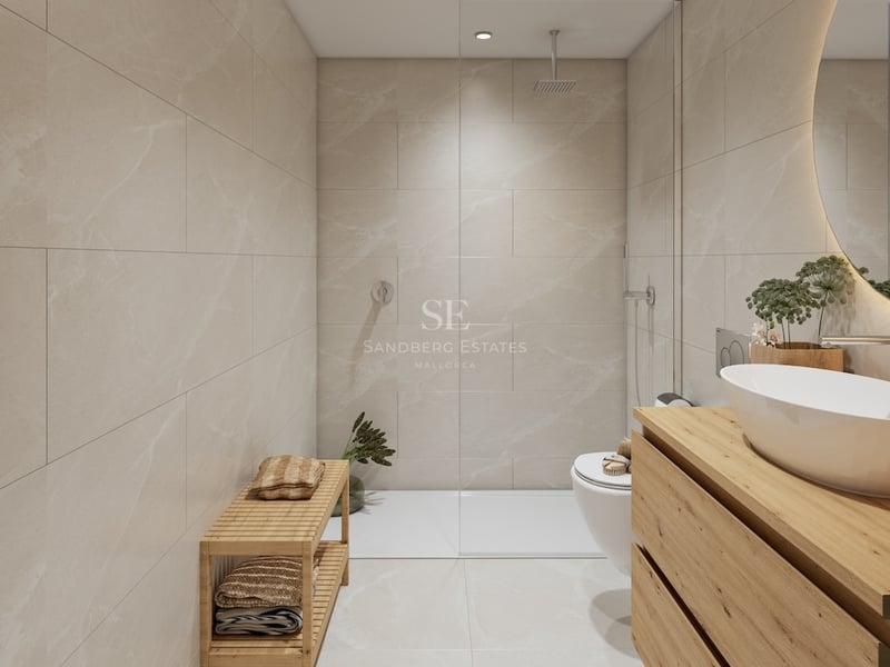 Modern bathroom with beige tiles, walk-in glass shower, wooden vanity, white vessel sink, and backlit circular mirror.