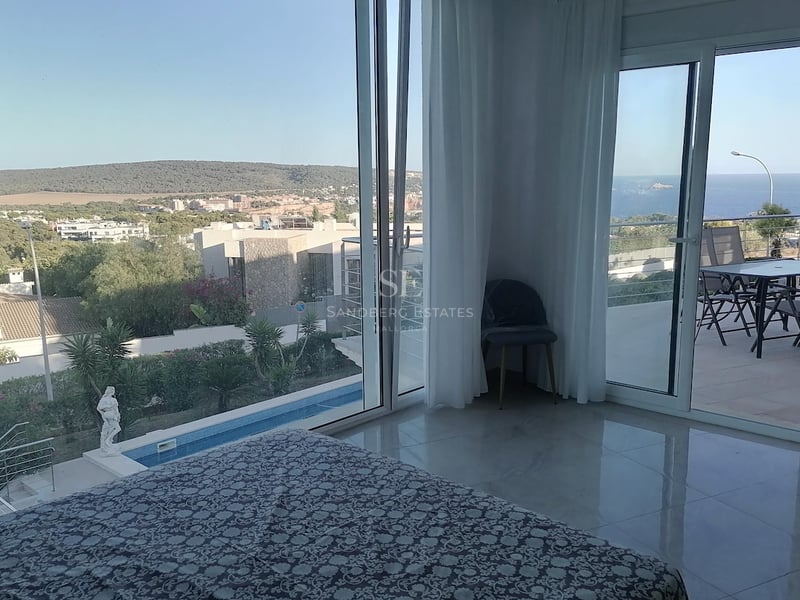 Chambre principale avec sol en marbre poli et baies vitrées ouvrant sur une terrasse dominant la mer et la piscine.