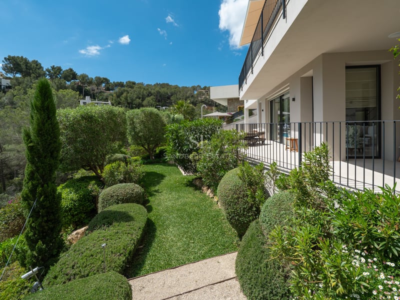Vue extérieure d'une villa moderne avec piscine à débordement. Grandes baies vitrées, design minimaliste et jardin tropical luxuriant.