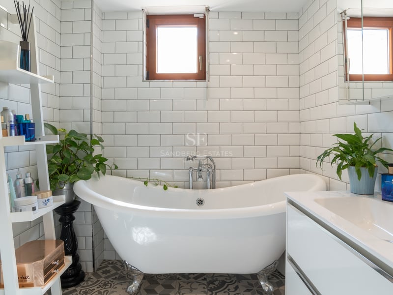 Salle de bains lumineuse avec baignoire sur pieds, carreaux de métro blancs et meuble vasque contemporain.