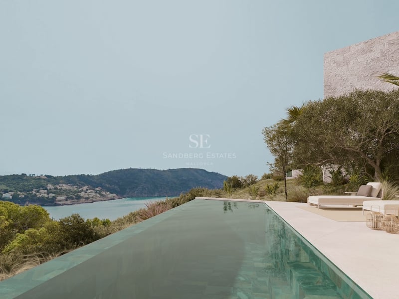 Infinity-Pool auf einer Steinterrasse mit Blick auf eine türkisfarbene Bucht und grüne Hügel.