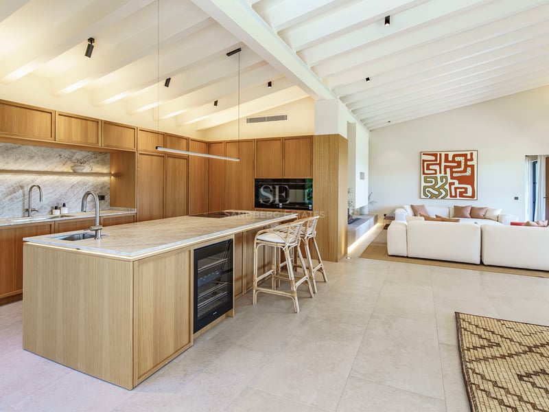 Moderne offene Küche mit hellen Holzschränken, Marmorinsel und weißer Balkendecke.