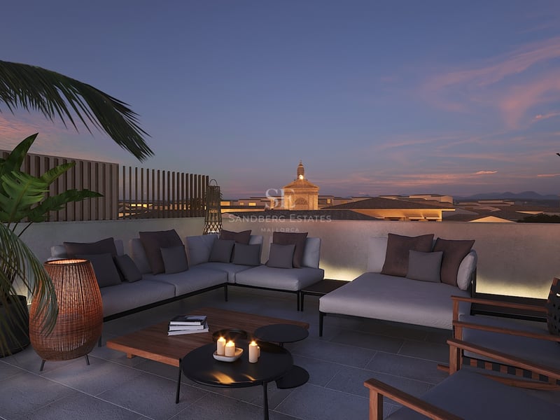 Salon de toit luxueux avec canapés gris et éclairage chaleureux surplombant une ville méditerranéenne au crépuscule.