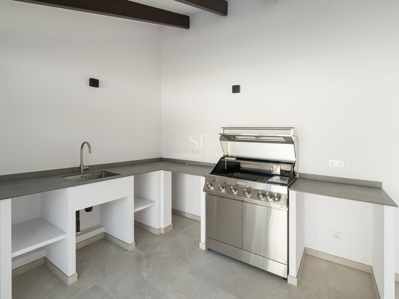 Cuisine extérieure contemporaine avec grill en inox, évier intégré et plans de travail gris.