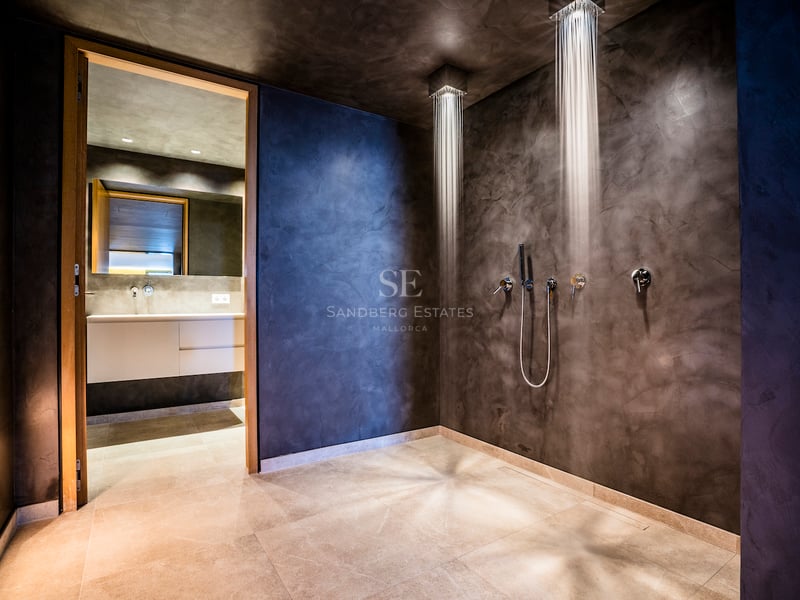 Moderne begehbare Dusche mit zwei Decken-Regenbrausen und anthrazitfarbenen Mikrozementwänden.