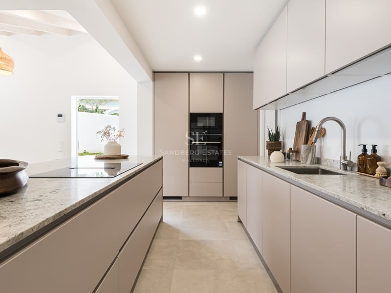 Cuisine contemporaine beige avec plans de travail en granit, îlot central et appareils électroménagers intégrés.