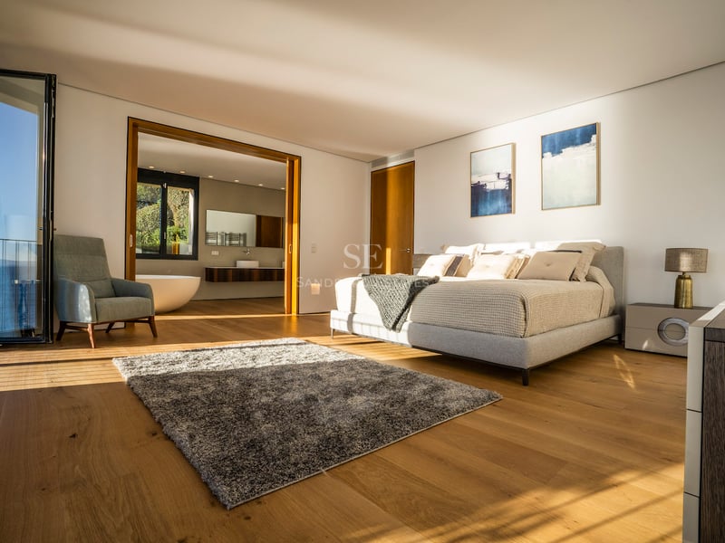 Modernes Hauptschlafzimmer mit Eichenparkett, Terrasse mit Meerblick und offenem En-Suite-Badezimmer.