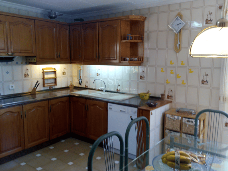 Cocina de estilo rústico con muebles de roble, azulejos decorativos beige y zona de comedor.