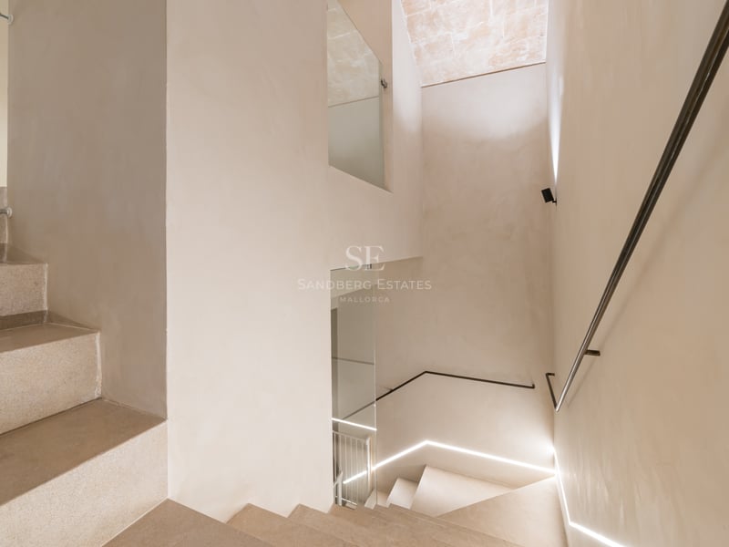 Escalier intérieur minimaliste avec marches en pierre claire, parois en verre et éclairage LED intégré au mur.