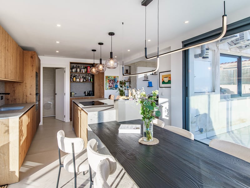 Cuisine moderne avec îlot en pierre et table à manger en bois noir avec chaises en bouclé crème.