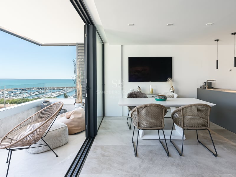 Modernes Esszimmer und Terrasse mit Glasgeländer mit Blick auf einen Jachthafen und das Mittelmeer.