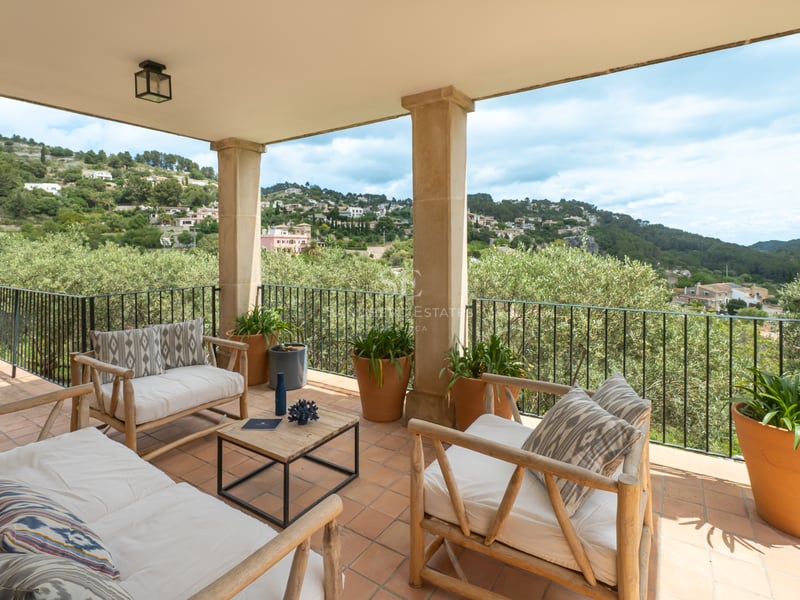 Terrasse couverte avec sol en terre cuite, mobilier en bois et vue sur les montagnes de Majorque.