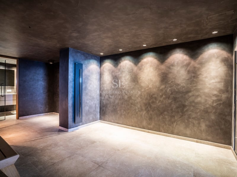 Minimalistischer Spa-Bereich mit dunkel strukturierten Wänden, Spotbeleuchtung und hellem Steinboden.