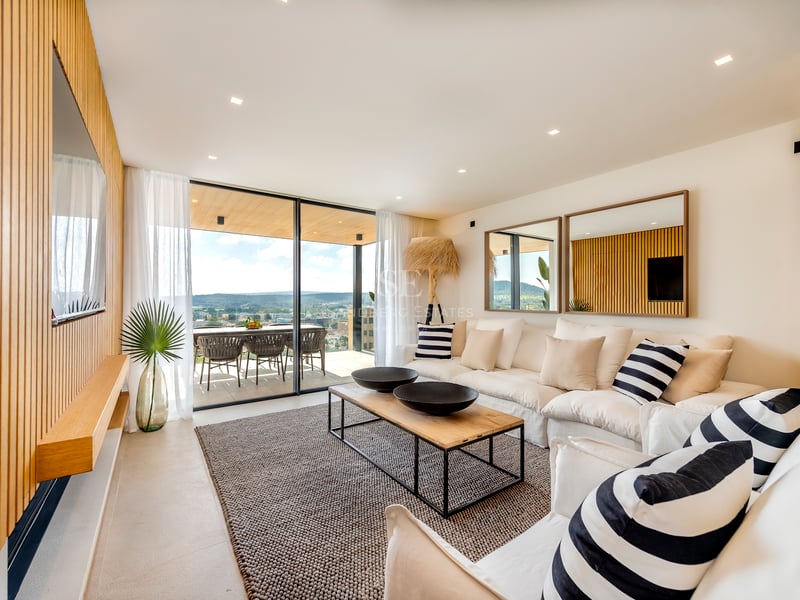 Salon contemporain avec boiseries en chêne, canapés blancs et grandes baies vitrées ouvrant sur une terrasse.