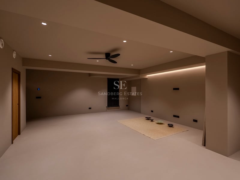 Pièce minimaliste vide avec murs beiges, éclairage LED indirect et ventilateur de plafond noir moderne.