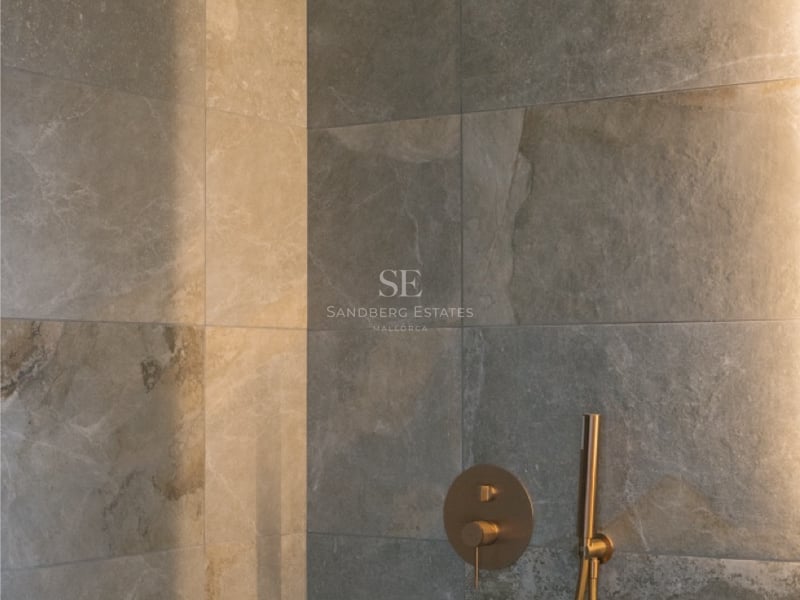 Luxuriöse Dusche mit großformatigen Natursteinfliesen und Regendusche in gebürstetem Messing mit LED-Lichtleiste.