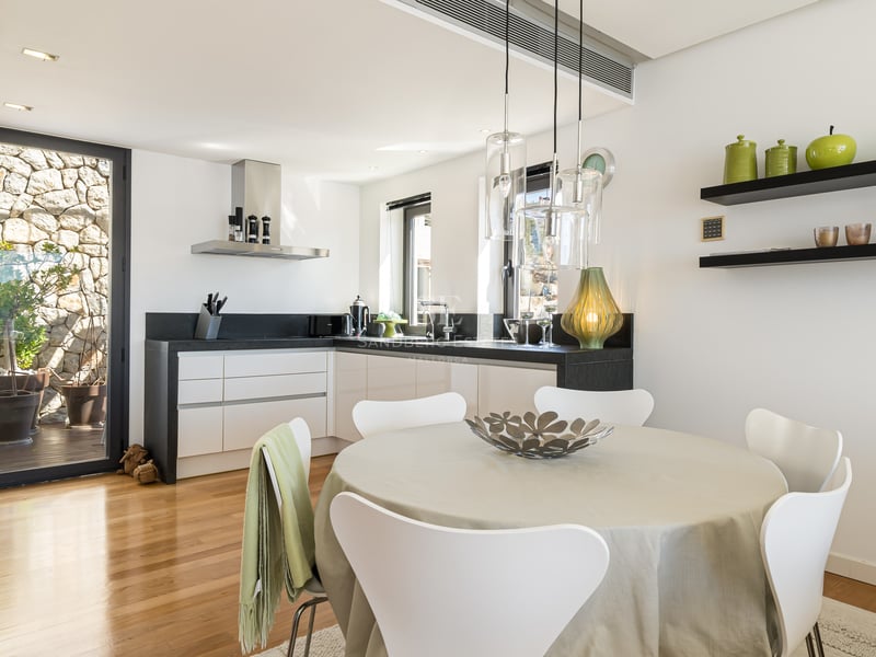 Bright kitchen with white cabinetry, black countertops, wooden floors, and a round dining table.