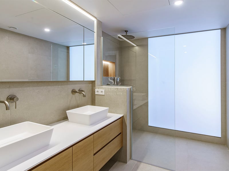 Salle de bain moderne avec double vasque en bois, lavabos blancs et douche à l'italienne avec verre dépoli.